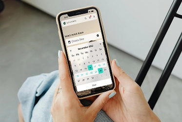 A woman selecting dates on a calendar screen to book infant car seat hire.